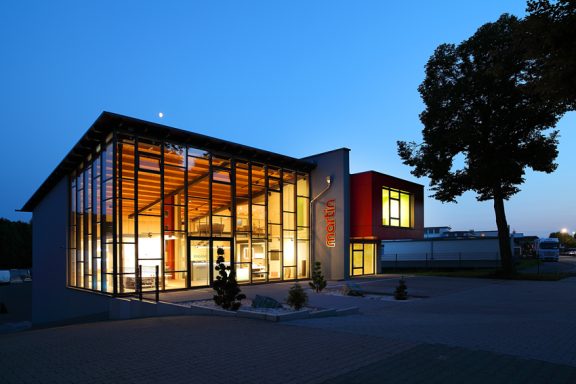 Ausstellung von Außen Moderne Architektur mit Glasfront und heller Beleuchtung bei Dämmerung.