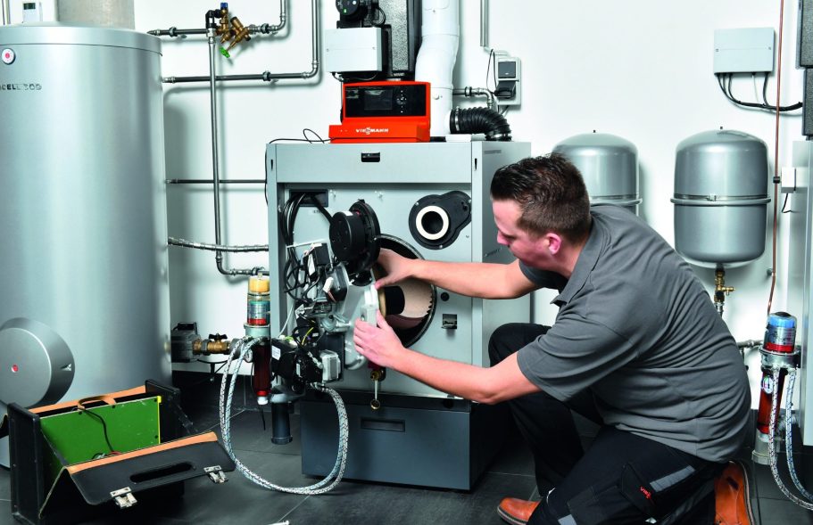 Kundendienst Ein Techniker wartet eine Heizungsanlage und prüft deren Komponenten.